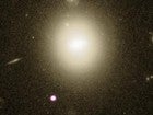 Una brillante galaxia situada a 740 millones de años luz alberga un agujero negro intermedio que desgarra una estrella (abajo, en morado)