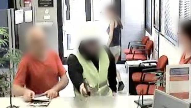 Fotograma del video de seguridad del banco, en el que aparece el atracador, pistola en mano