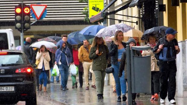 Transeúntes caminando bajo la lluvia por el centro de Alicante