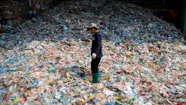 Un trabajador de un vertedero, rodeado de botellas de plástico